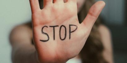 Eine Frau hält ihre Han in die Kamera, darauf steht "Stop"