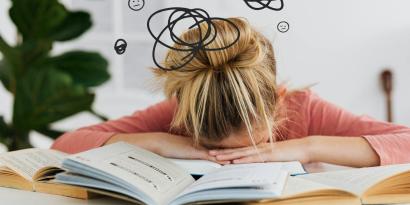 Frau stützt den Kopf auf Bücher