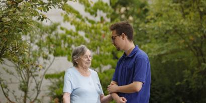 Junger Pfleger mit Seniorin im Garten
