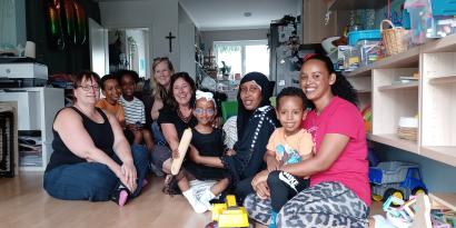 Frauen mit und ohne Migrationshintergrund und Kinder sitzen am Boden