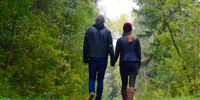 Ein Paar läuft Hand in Hand durch den Wald.