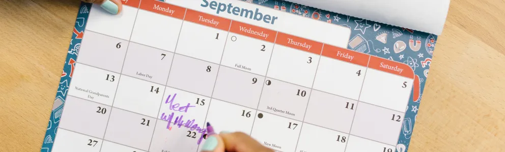Frau trägt Termin in den Kalender ein
