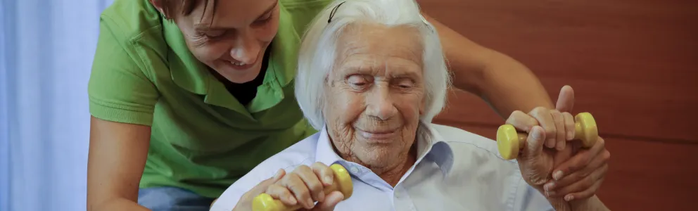 Pflegekraft aktiviert Seniorin mit Hanteln