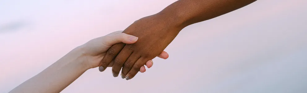 Weiße Hand greift nach schwarzem Arm 
