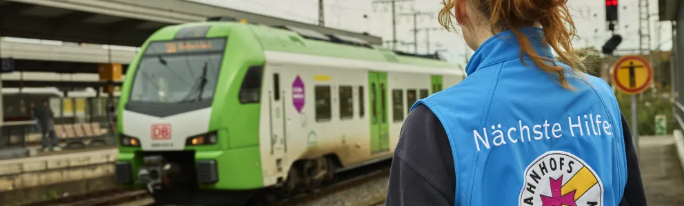 Mitarbeiterin der Bahnhofmission schaut auf Zug