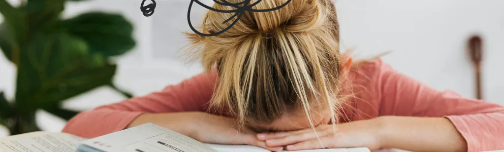 Frau stützt den Kopf auf Bücher