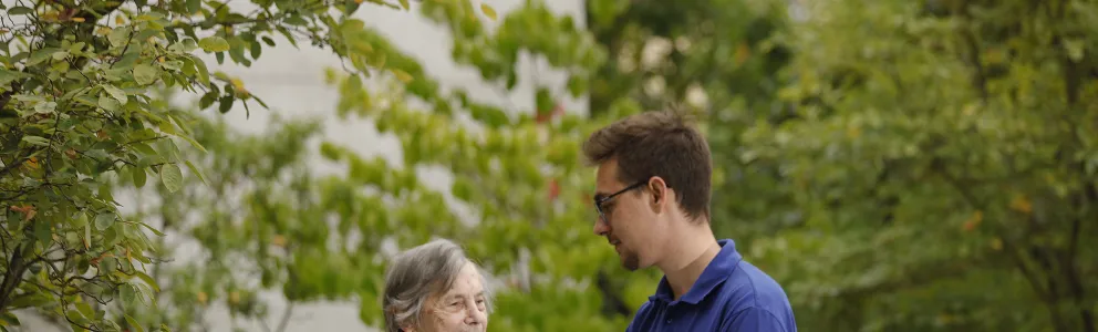 Junger Pfleger mit Seniorin im Garten