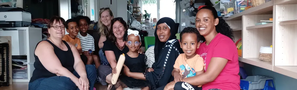 Frauen mit und ohne Migrationshintergrund und Kinder sitzen am Boden