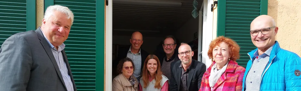 Spender und Diakonievertreter an einem Fenster mit neuen Fensterläden.