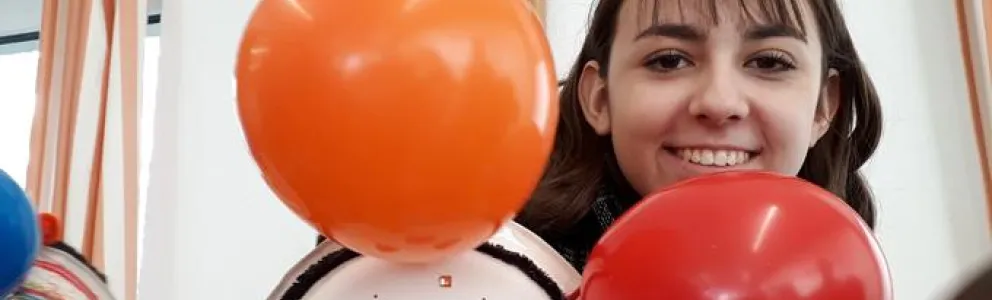Junge Frau sieht hinter zwei Luftballons hervor