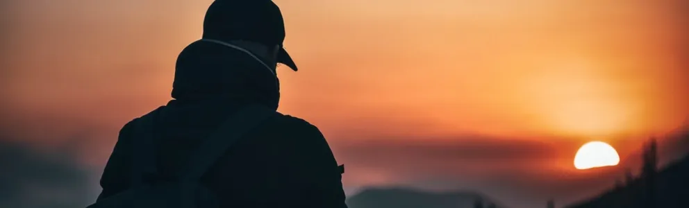 Mann steht auf einem Berg und beobachtet den Sonnenaufgang