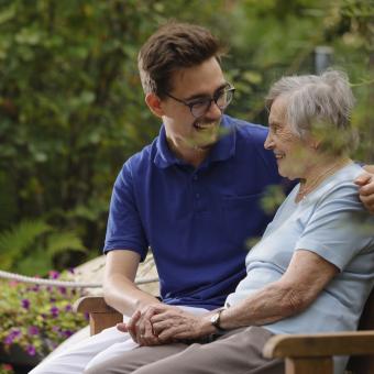 Pflegekraft umarmt Seniorin herzlich