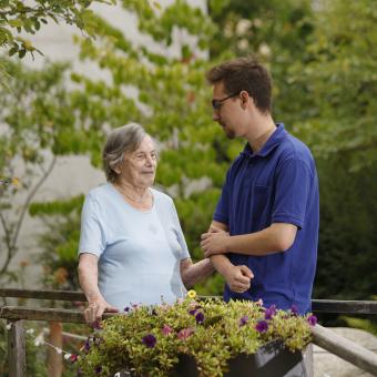Junger Pfleger mit Seniorin im Garten