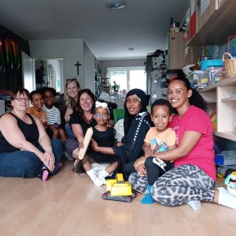 Frauen mit und ohne Migrationshintergrund und Kinder sitzen am Boden