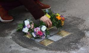 Eine Frau legt Blumen auf die neu eingesetzten Stolpersteine vor dem Bodelschwingh-Haus.